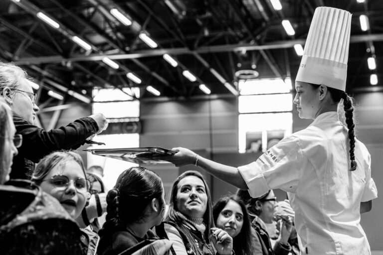 Jeune pâtissière servant le public - Dégustation de créations sucrées - Expérience culinaire au Salon du Chocolat - Photographe événementiel
