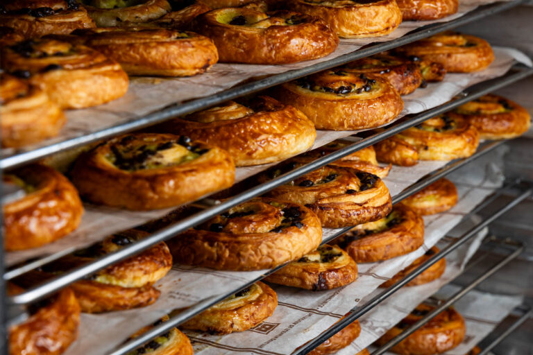 Pains aux raisins dorés sur étagères - Viennoiseries fraîchement sorties du four - Perfection du feuilletage en boulangerie - Reportage photo professionnel