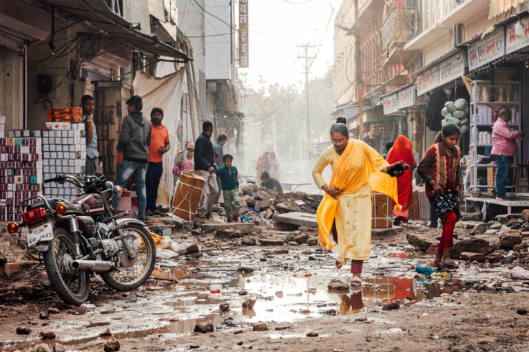 Femme en sari jaune dans ruelle boueuse - Marché urbain désordonné en Inde - Scène de vie populaire - photographe Nantes