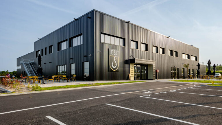 Façade noire bâtiment sportif - Le Set - Complexe sportif multisport Le Bignon - Terrasse extérieure avec mobilier jaune - Reportage photo architecture - Agence Brunet-Monié