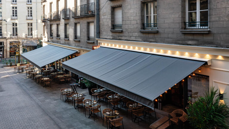 Terrasse de restaurant couverte - Store banne gris déployé - Photo d’aménagement extérieur - Agence Brunet-Monié