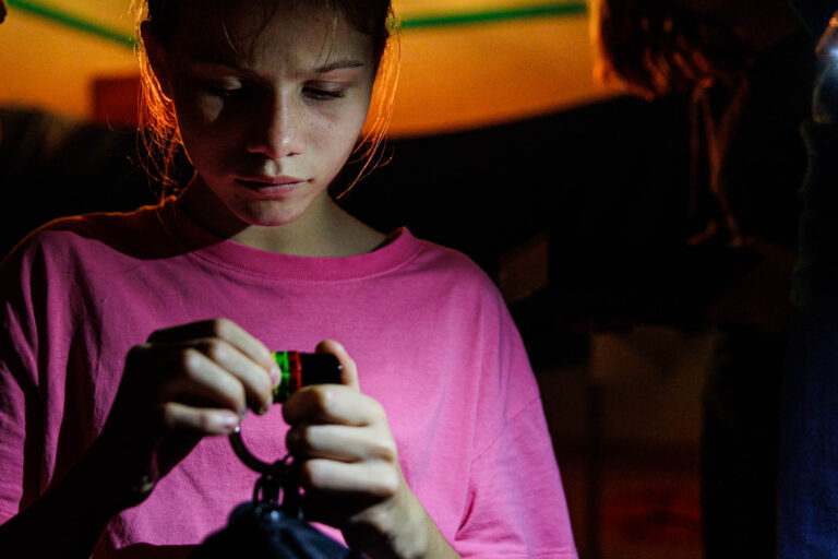 Fille concentrée avec lampe torche - Activité nocturne escape game - Animation immersive enfant - Agence photo à Nantes