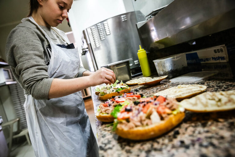 Préparation de sandwichs frais - Employée concentrée sur garniture - Photographie de métier manuel - prestataire photo nantes
