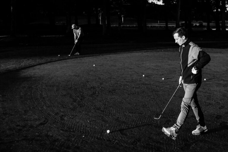 Golfeur concentré en putting - Ombres marquées en fin de journée - Photoreportage terrain golf - Agence Brunet-Monié