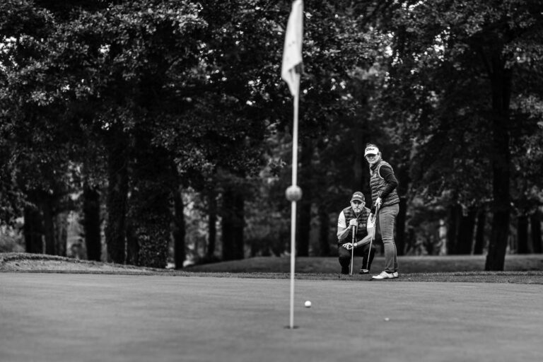 Duo de golfeurs en préparation - Cadrage profond sur green et drapeau - Photoreportage sportif - photographe nantes