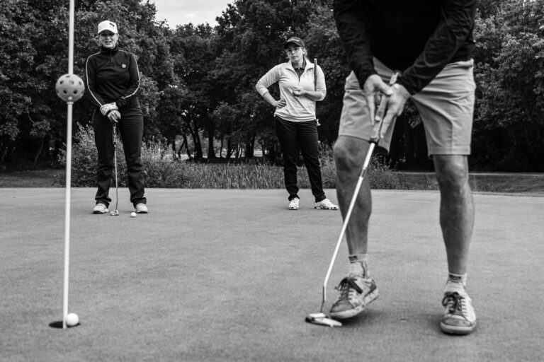 Golfeur concentré putt final - Équipe en discussion autour du green - compétition de golf - Agence Brunet-Monié