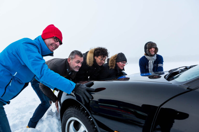 Participants poussant voiture sportive - Effort collectif sur glace - Reportage événementiel à l’étranger - Agence Brunet-Monié