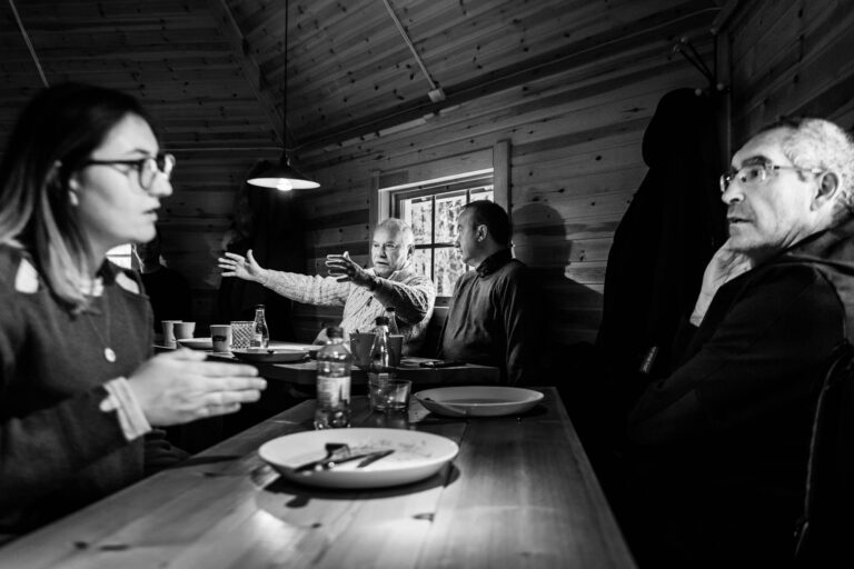 Participants autour table chalet - Discussion conviviale en intérieur - Photoreportage vie de groupe - prestataire photo Nantes