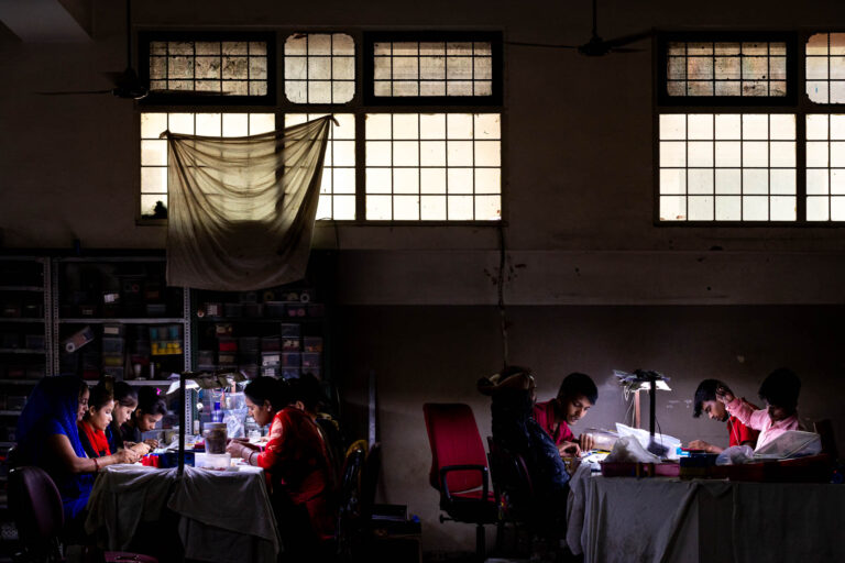 Femmes et hommes travaillant table - Éclairage atelier bijouterie Jaipur - Photoreportage quotidien usine - Agence Brunet-Monié