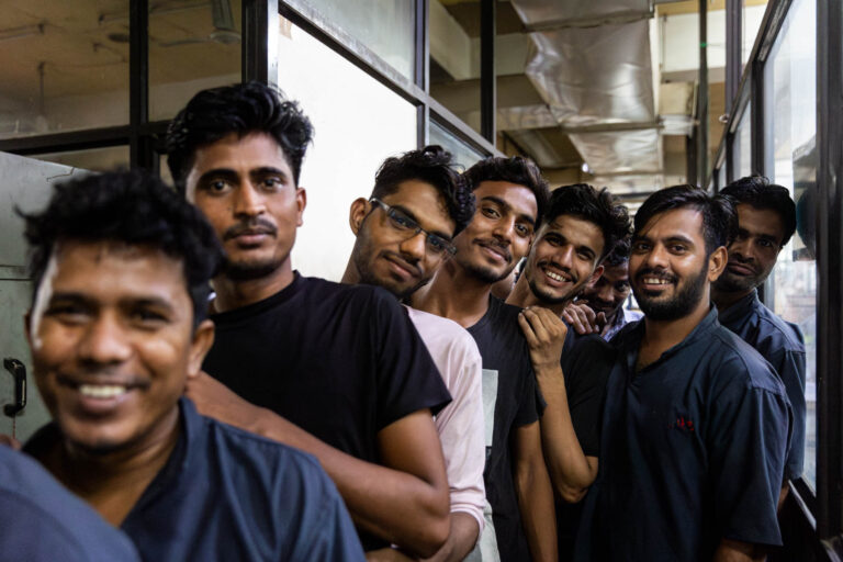 Groupe ouvriers indiens souriants - Alignement file attente atelier - Reportage documentaire humain - Agence photo à Nantes