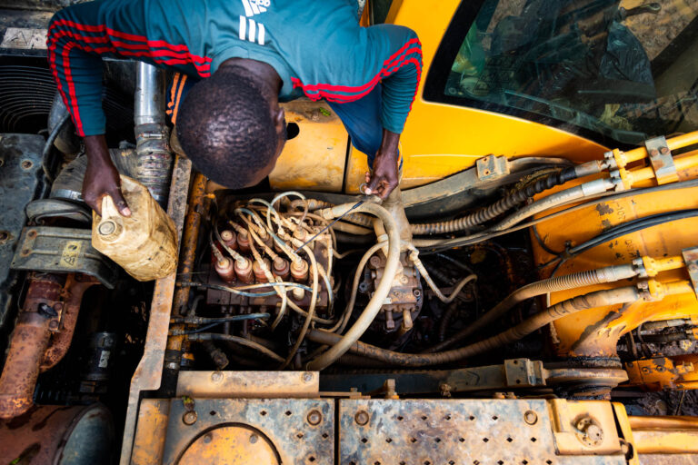 Mécanicien réparant engin de chantier - Entretien moteur pelleteuse Hyundai - Mines légales en Guyane - studio photo loire-atlantique
